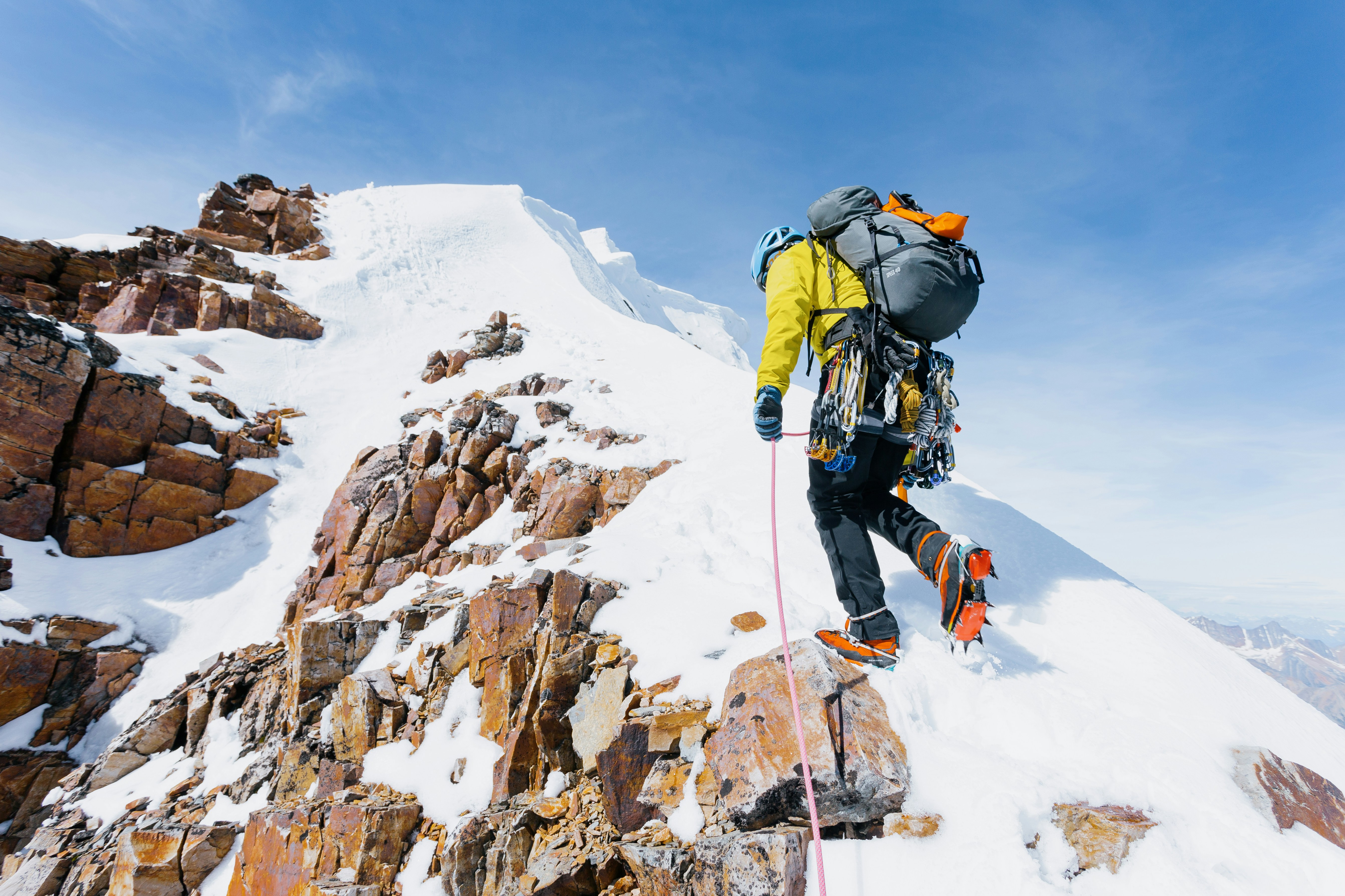 A climber ascending a snowy mountain ridge